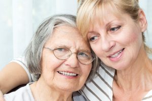 Beautiful mature daughter hugging her senior mother.